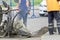 Repair of city roads and replacement of worn asphalt concrete pavement. A worker with a shovel throws concrete into a pit to