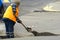 Repair of city roads and replacement of worn asphalt concrete pavement. A worker with a shovel throws concrete into a pit to