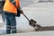 Repair of city roads and replacement of worn asphalt concrete pavement. A worker with a shovel throws concrete into a pit to