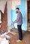 Repair in the home. A young man knocks down old Soviet-era plasterboard slabs from the wall with iron scrap. Visible brick wall ba