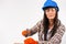 Repair woman hammering a nail on white looks into the camera wearing protective glasses and hardhat. Gender stereotypes