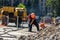 Repair work on the city street. Professional workers dismantle part of the road with a professional tool. Workers remove the