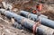 Repair work of heating duct. The workers, welders made by electric welding on large iron pipes at a depth of excavated trench