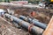 Repair work of heating duct. The workers, welders made by electric welding on large iron pipes at a depth of excavated trench