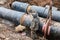 Repair work of heating duct. The workers, welders made by electric welding on large iron pipes at a depth of excavated trench