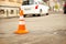 Repair work sign restricting traffic. White-orange plastic striped cone warning of danger. Tightening in traffic. Street of the