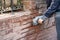 Repairing broken brick wall. Women cleaning grouts with a grinder.