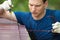 Repairman in blue suit cleans and strengthens the roof surface, close-up