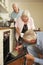 Repairman Fixing Cooker In Senior Couple\'s Kitchen