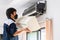 Repairman fixing modern air conditioner, Male technician cleaning air conditioner indoors, Maintenance and repairing concepts