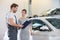 Repairman holding clipboard while conversing with female customer in automobile repair shop