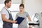 Repairman holding clipboard while conversing with female customer in repair shop