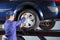 Repairman Inflating Tire Of Lifted Car