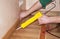 Repairman\'s hands Installing Skirting Board Oak Wooden Floor with Caulking Gu