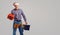 Repairman in Santa hat with a gift on a gray background.