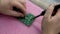 Repairman is soldering circuit board of electronic device on the table, hands close-up. Technician engineer in workshop.