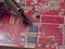 A repairman solders a printed circuit board of an electronic device in red color close-up. Repair and soldering of chips with a