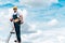 Repairman standing on ladder and smiling against blue sky with clouds