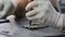 Repairman in white gloves disassembles smartphone with screwdriver in workshop.