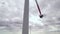 Repairmen fix wind turbine propeller blade under cloudy sky