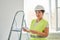 Repairs in the apartment, a girl in a green vest and a white helmet is in a white room with a tablet in her hands