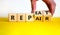 Repeat and repair symbol. Businessman turns wooden cubes and changes the word `repeat` to `repair`. Beautiful yellow table, wh