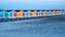 Repeating pattern of colorful beach storage units on sand with angled perspective