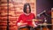 Repetition. Girl in red sweater passionately plays the drums in a studio.