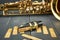 Replacement reeds and saxophone mouthpiece with clamp and golden adjustment screws on gray wooden table and tenor sax body in the