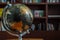Replica globe on the background of bookshelves in library