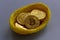 Replica of golden bitcoin in a bird nest. Grey background.