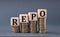 REPO - word on wooden cubes on coins on a gray background