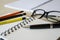 Representative pen laying on a blank note book with pencils and glasses on table. Tilt-up close-up view