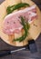 Repuised pork steaks on a wooden cutting board with dill and spices