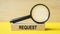 Request word through magnifying glass on wooden background