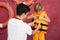 Rescuer putting orange life vest on child near red wall