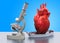 Research and diagnostics of heart disease concept. Laboratory microscope with human heart, 3D rendering