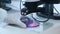 Research scientist in rubber gloves adjusts specimen in a Petri Dish under microscope. Microbiological research against