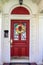 Resentails red front door with leaded glass in white house colorful Day of the Dead Halloween wreath