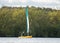 Reservoir small yellow sail boat on clean blue lake water in sunshine. Sailing alone.