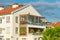 Residential building with roof tiles and large terraces with wooden elements, glass balconies and decorative leafy flowering