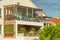 Residential building with roof tiles and large terraces with wooden elements, glass balconies and decorative leafy flowering