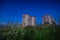 Residential buildings against a dark blue evening sky, bottom view. Typical housing that protrude above the green grass.