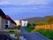 Residential buildings along the road in the light of the evening rays of the sun against a hole and a cloudy sky