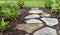 Residential garden walking path with flat stones, mulch and green plants