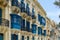 Residential house facade with traditional Maltese navy blue enclosed wooden balconies in Valletta, Malta