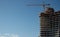 Residential office building construction site and cranes during a vibrant summer day with blue sky.