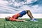 Resistance band training fit man doing bridge exercise fitness athlete doing glute workout outside on grass