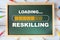 Reskilling loading written on chalkboard with coloured pencil on wooden