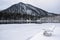 A resort on the lake in winter. Wooden chairs in the snow by a frozen lake.